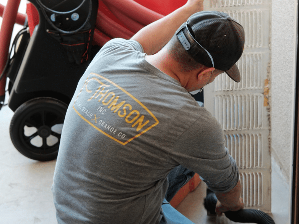 Thomson technician in branded uniform servicing HVAC equipment