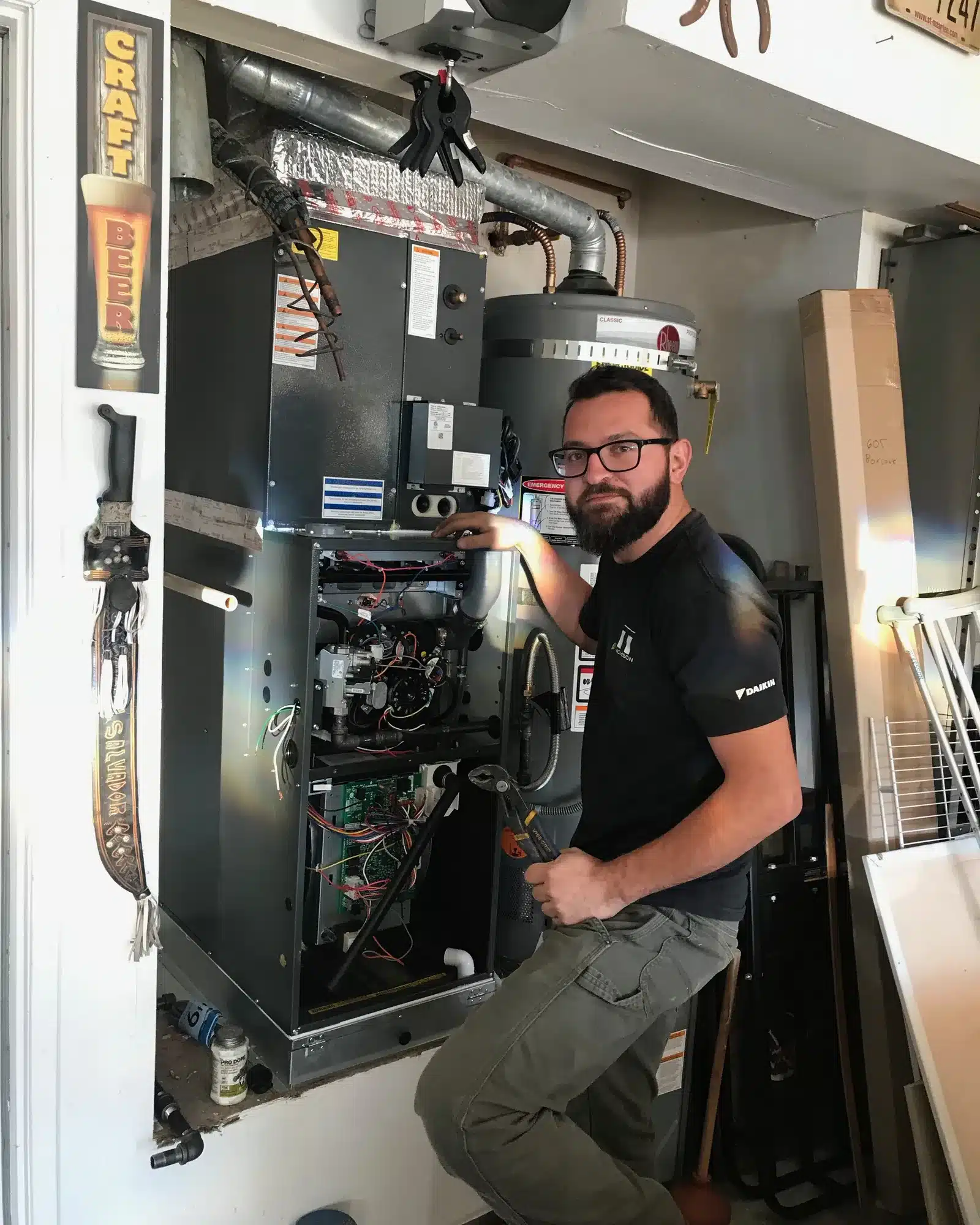 Thomson AC technician next to an open gas furnace in a garage