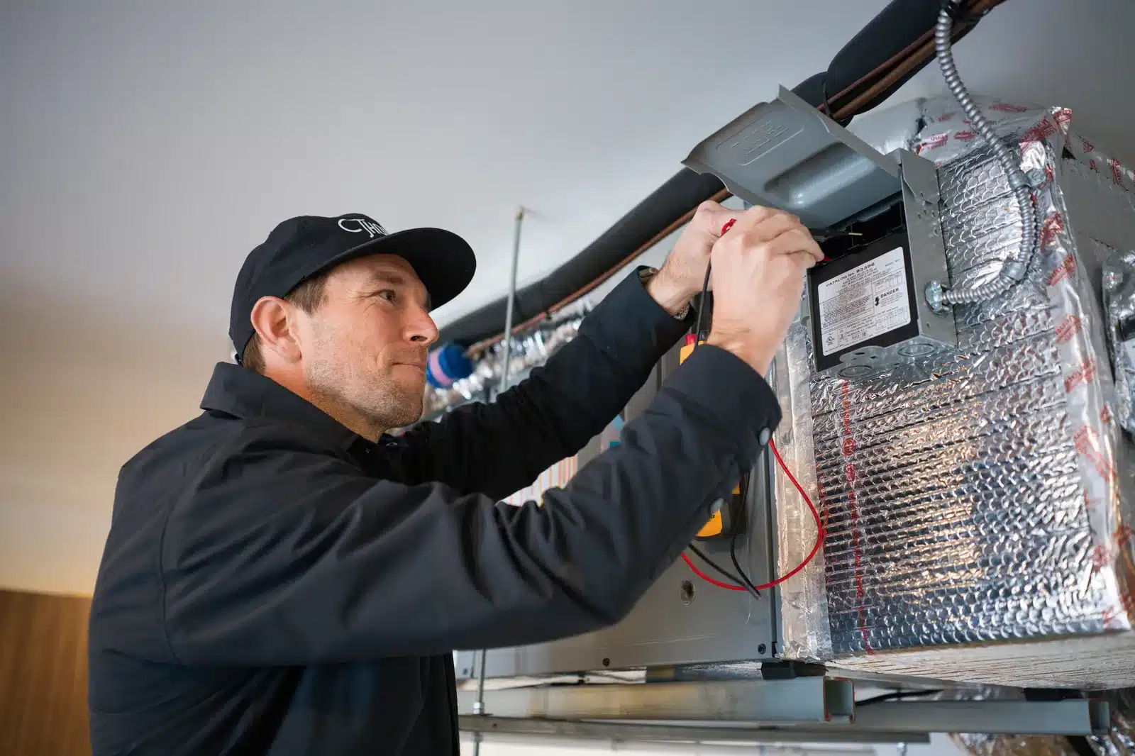 Thomson AC technician testing the controls on an indoor heating unit