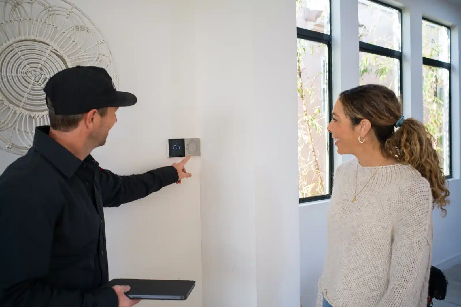 Thomson AC technician showing a homeowner her thermostat settings