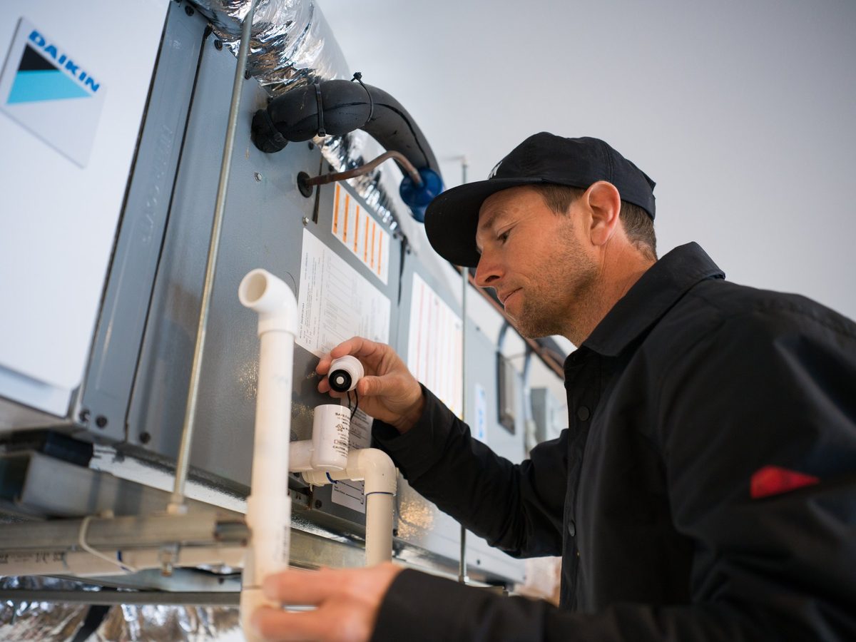 Thomson technician checking an HVAC system during a maintenance visit